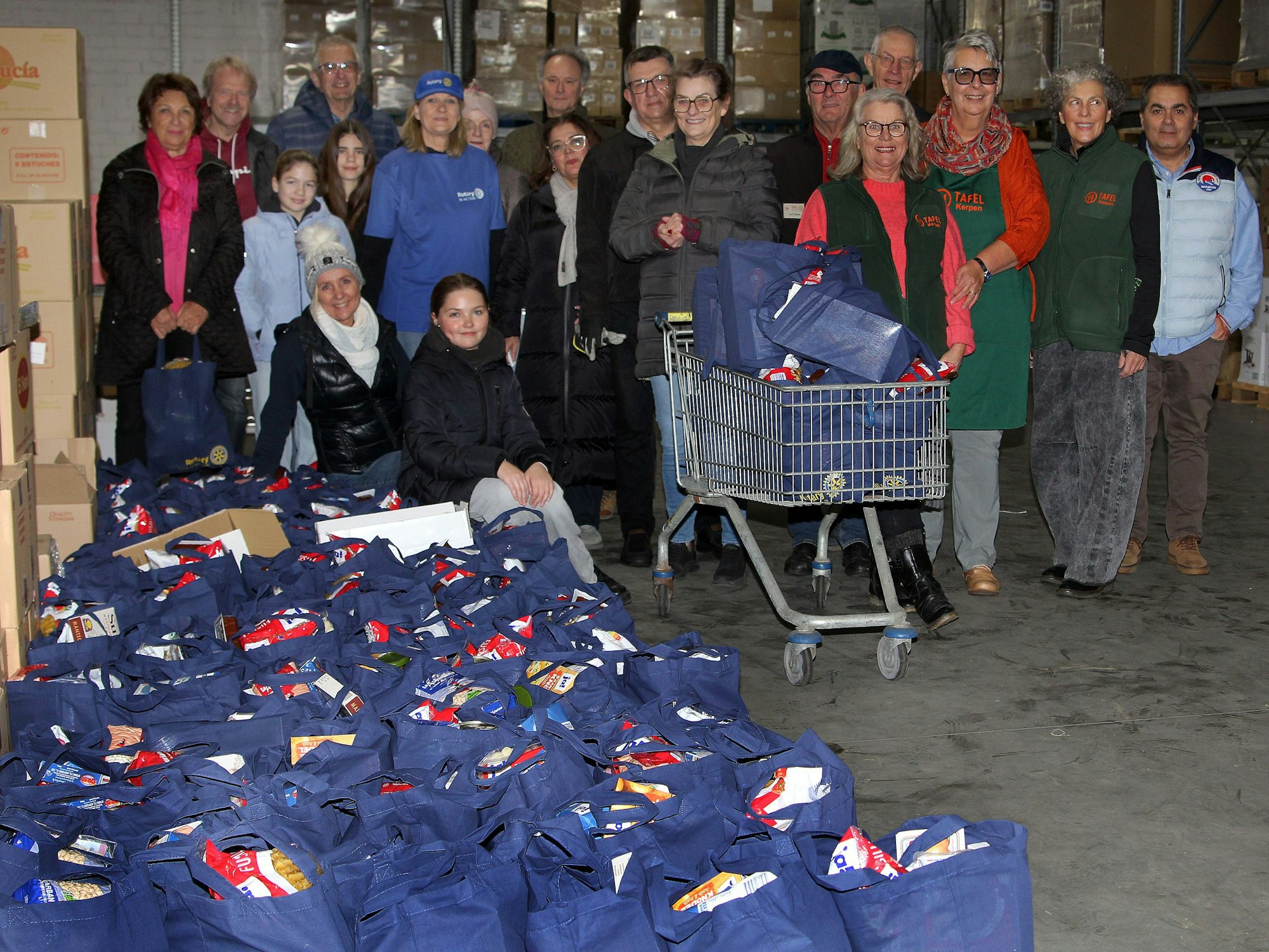 Auf dem Bild ist eine Gruppe zu sehen, die Stoffbeutel mit Lebensmitteln für die Tafeln gepackt hat.