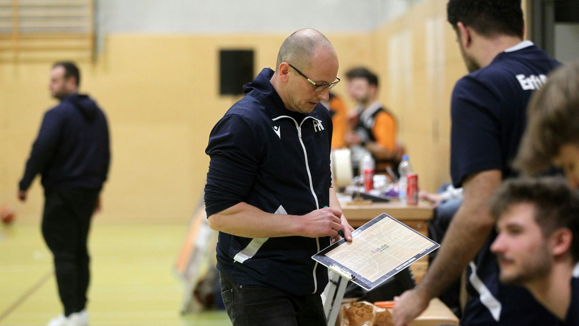 Florian Hammes hält ein Klemmbrett in der Hand.