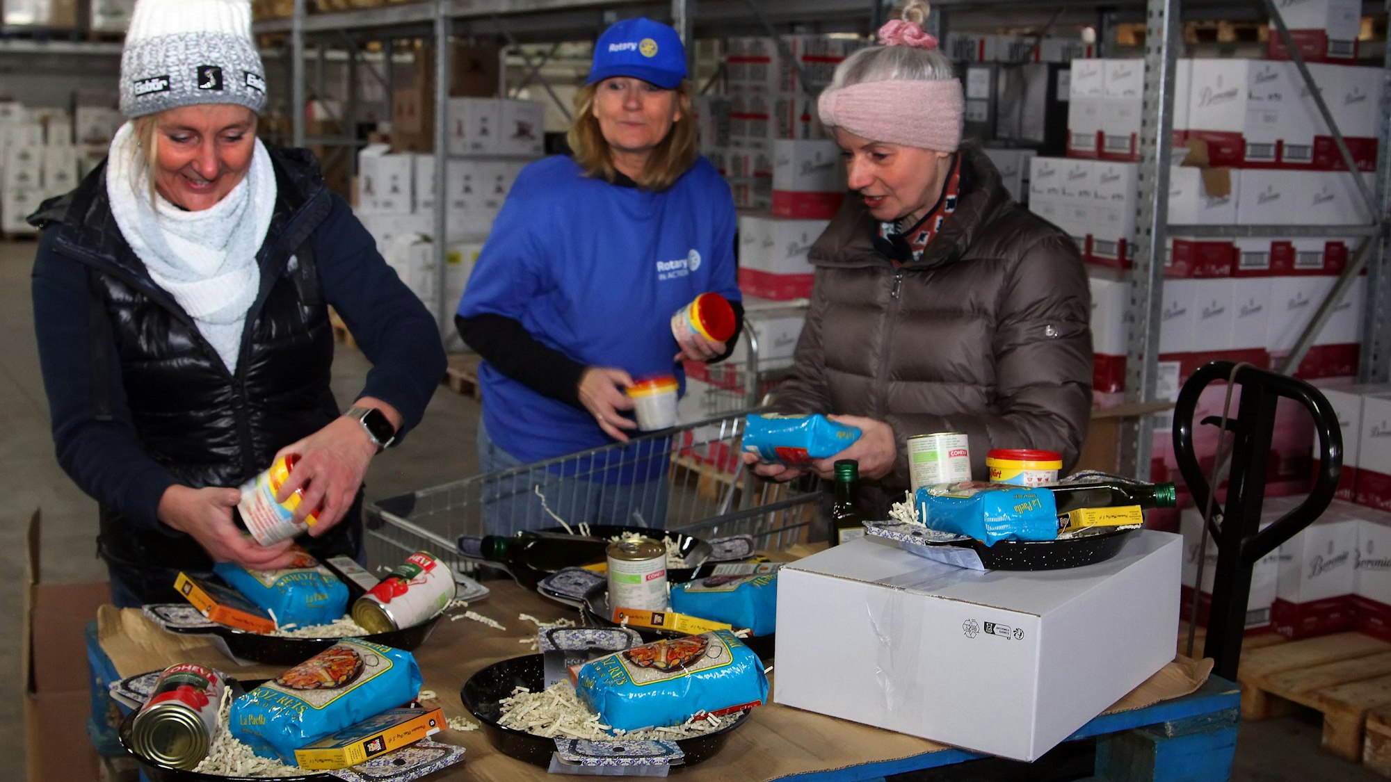 Drei Frauen packen Pakete in einem Lager.
