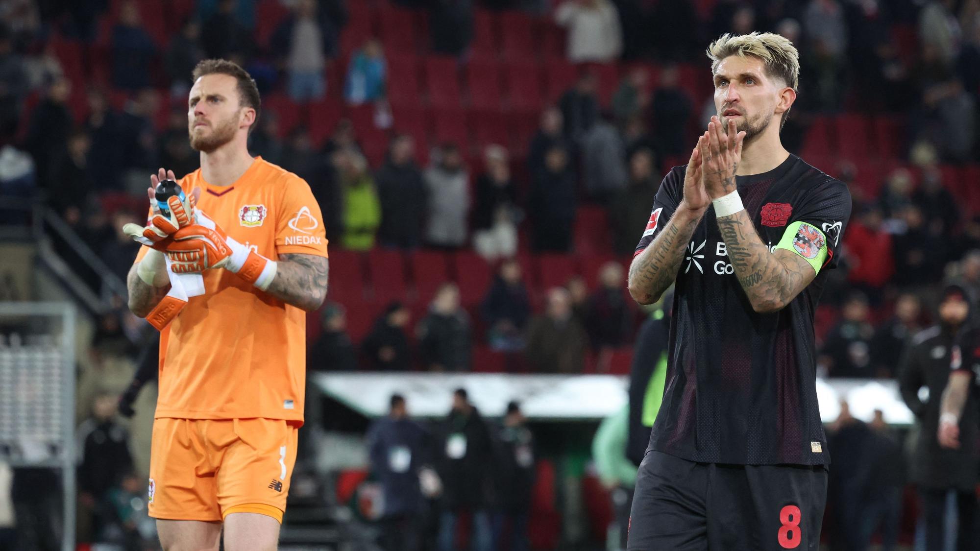 Bayer Leverkusen's German midfielder #08 Robert Andrich (R) and Bayer Leverkusen's Dutch goalkeeper #01 Mark Flekken clap hands after the end of the German first division Bundesliga football match between FC Augsburg and Bayer Leverkusen in Augsburg, southern Germany, on December 6, 2025. (Photo by Karl-Josef HILDENBRAND / AFP) / DFL REGULATIONS PROHIBIT ANY USE OF PHOTOGRAPHS AS IMAGE SEQUENCES AND/OR QUASI-VIDEO
