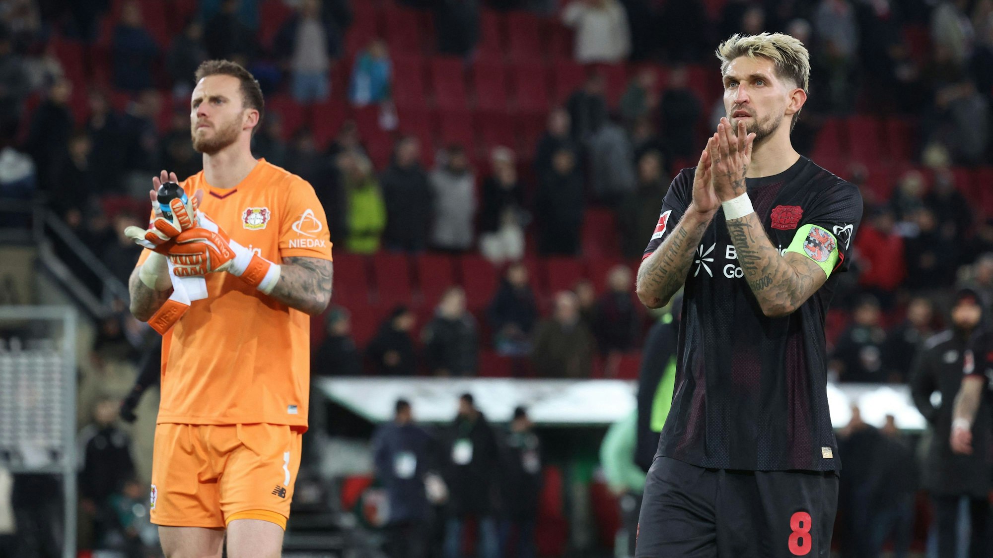 Bayer Leverkusen's German midfielder #08 Robert Andrich (R) and Bayer Leverkusen's Dutch goalkeeper #01 Mark Flekken clap hands after the end of the German first division Bundesliga football match between FC Augsburg and Bayer Leverkusen in Augsburg, southern Germany, on December 6, 2025. (Photo by Karl-Josef HILDENBRAND / AFP) / DFL REGULATIONS PROHIBIT ANY USE OF PHOTOGRAPHS AS IMAGE SEQUENCES AND/OR QUASI-VIDEO