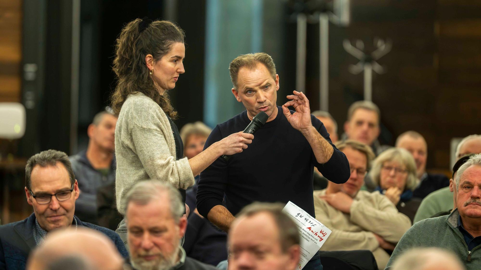 Stephan Brock spricht in das Mikrofon, das eine Frau hält. Um ihrn herum sitzt Publikum.