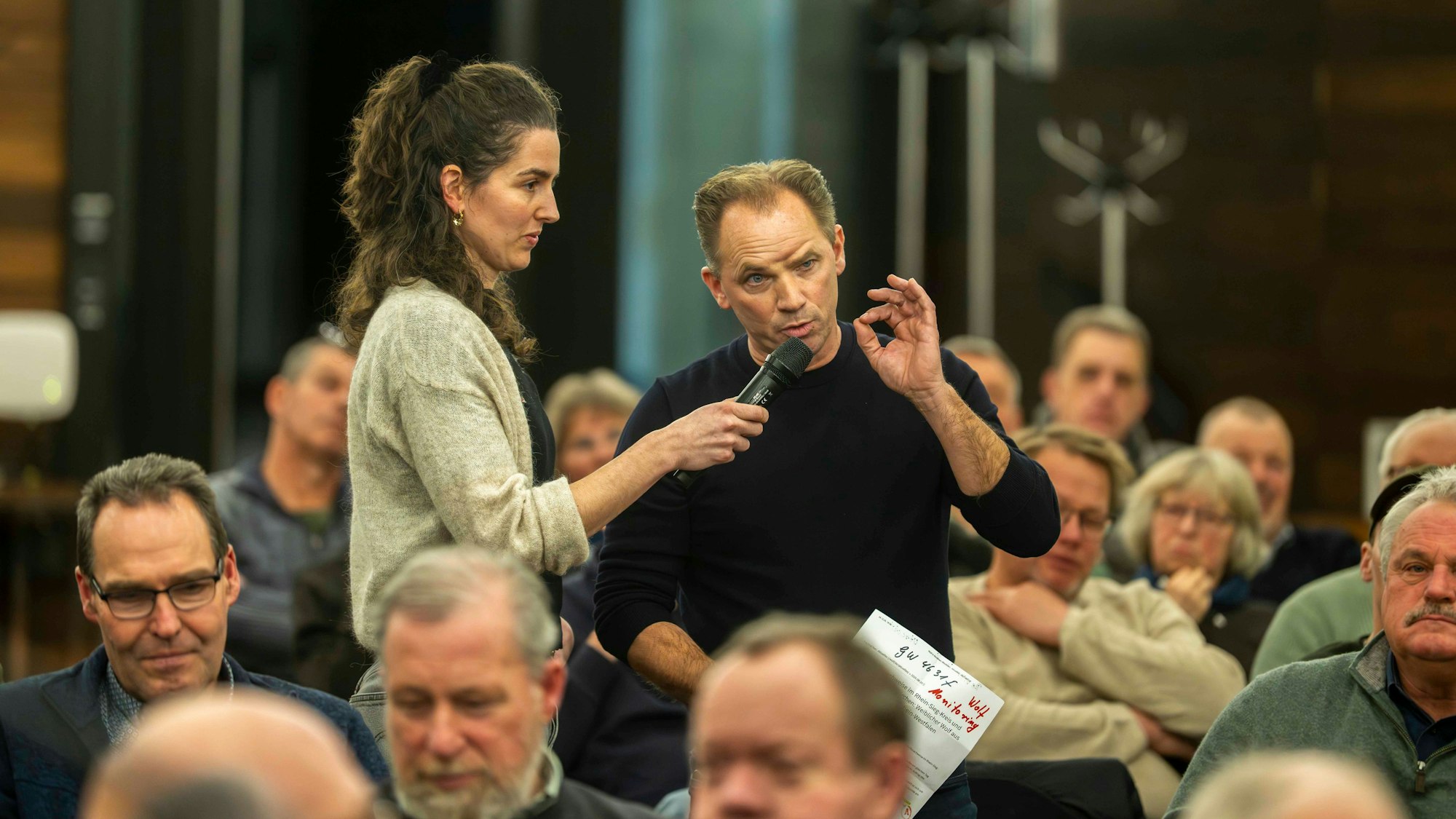 Stephan Brock spricht in das Mikrofon, das eine Frau hält. Um ihrn herum sitzt Publikum.