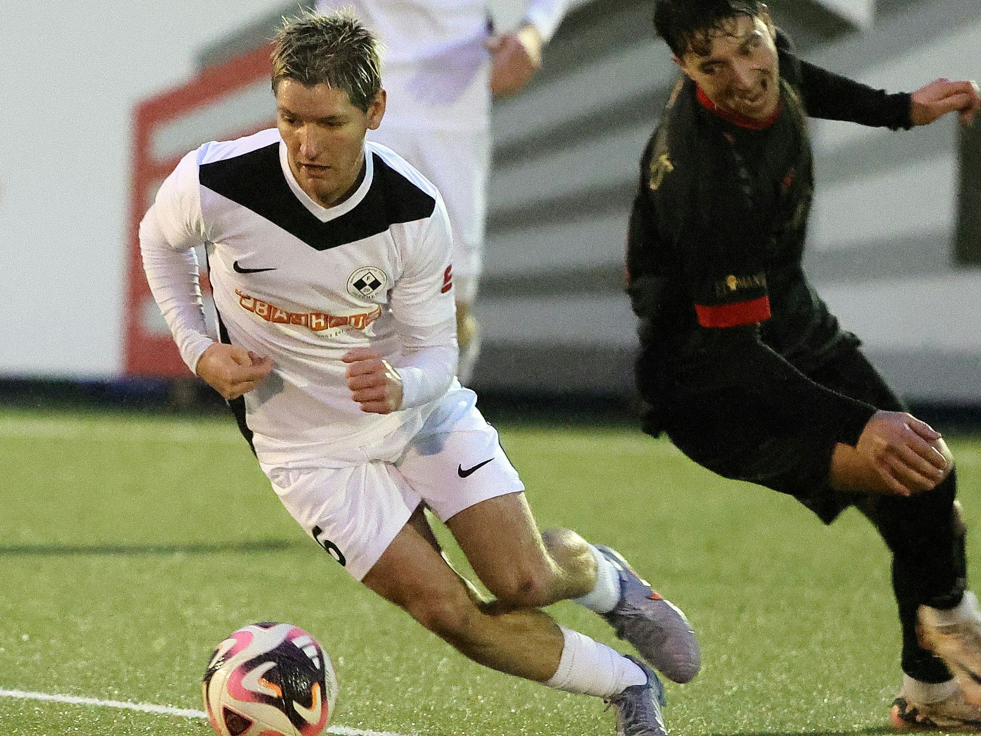 Auf dem Foto ist ein Spieler der SpVg Frechen 20, der seinen Gegenspieler mit dem Ball am Fuß elegant umkurvt.