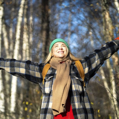 Eine Frau hebt die Arme und lächelt. (Symbolbild)