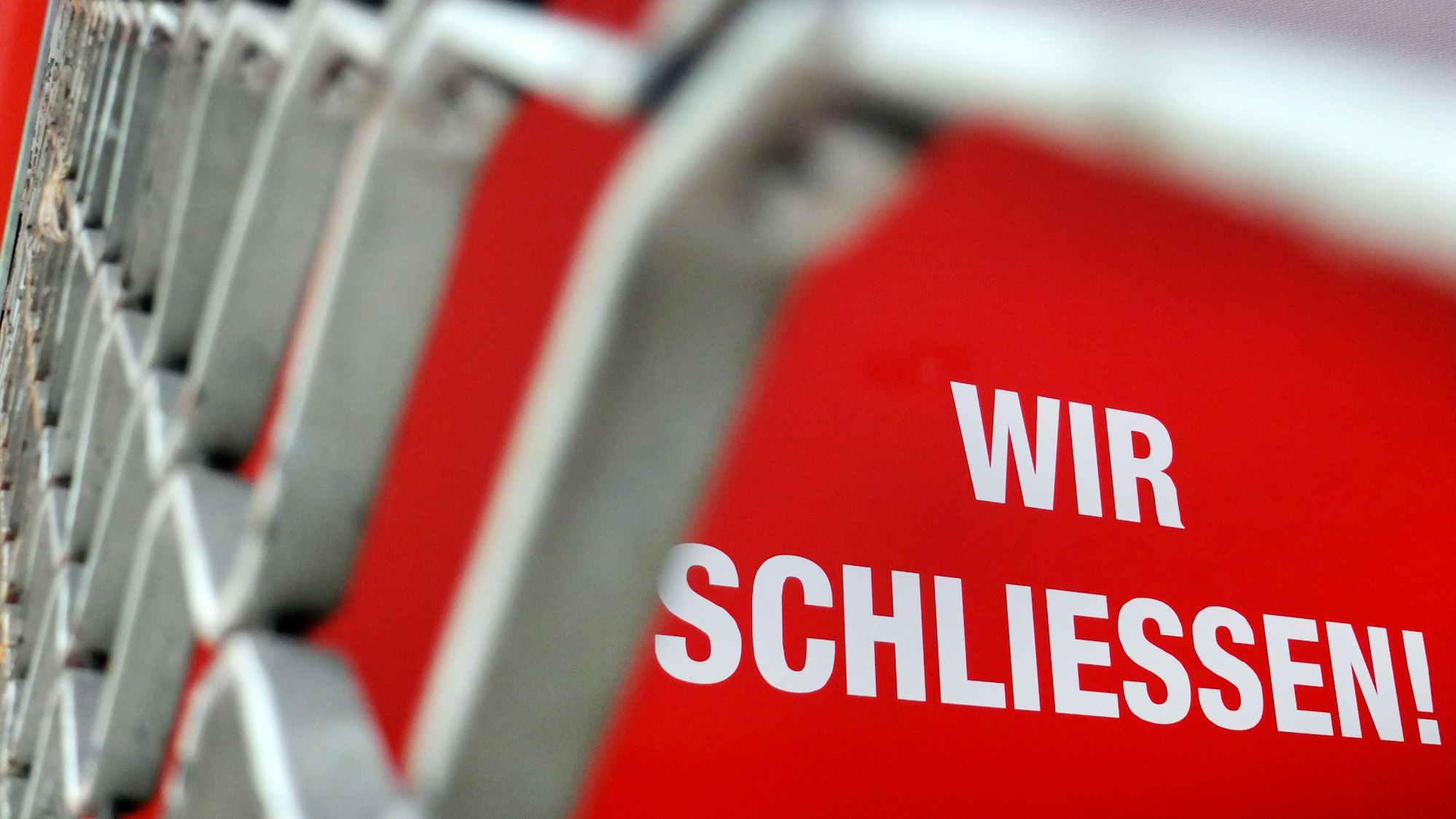 Der Schriftzug „Wir Schliessen“ steht hinter einem Rollgitter an einem geschlossenen Geschäft.