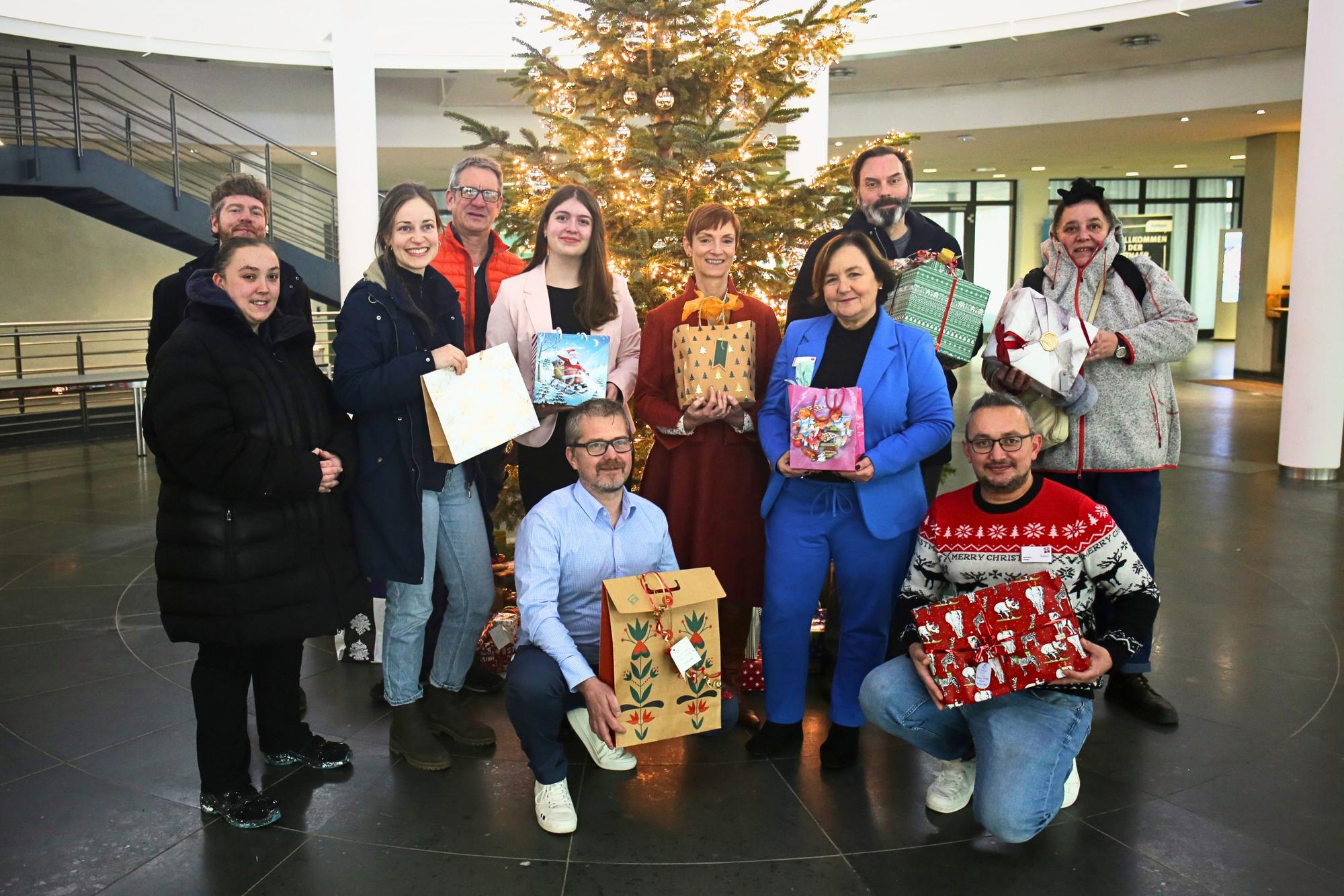 Angestellte der Barmenia-Gothaer mit Spenden-Paketen vor dem geschmückten Weihnachtsbaum.