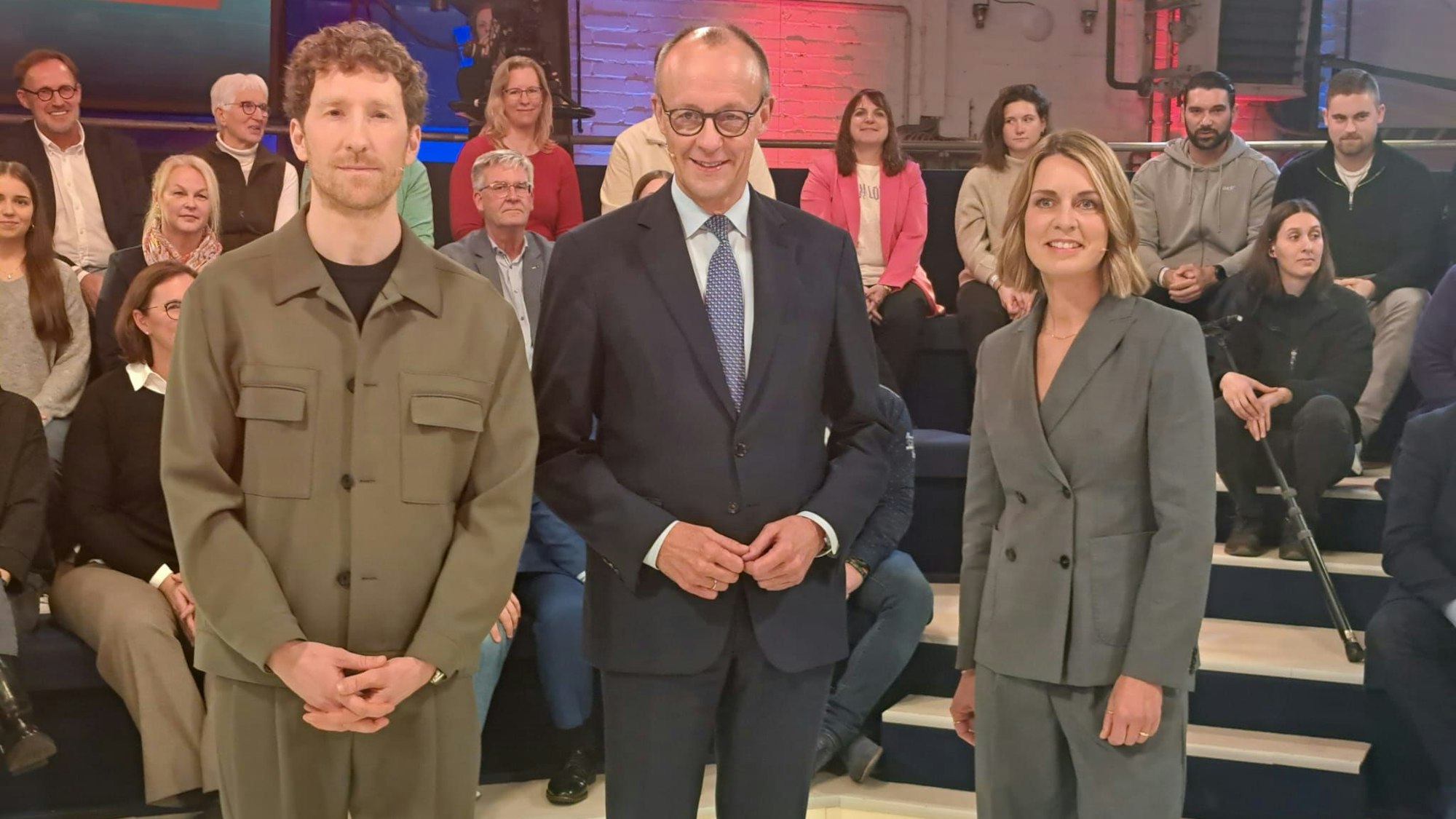 Vor der Sendung, das Publikum sitzt. Und Friedrich Merz posiert mit Moderator Louis Klamroth (l.) und Jessy Wellmer.