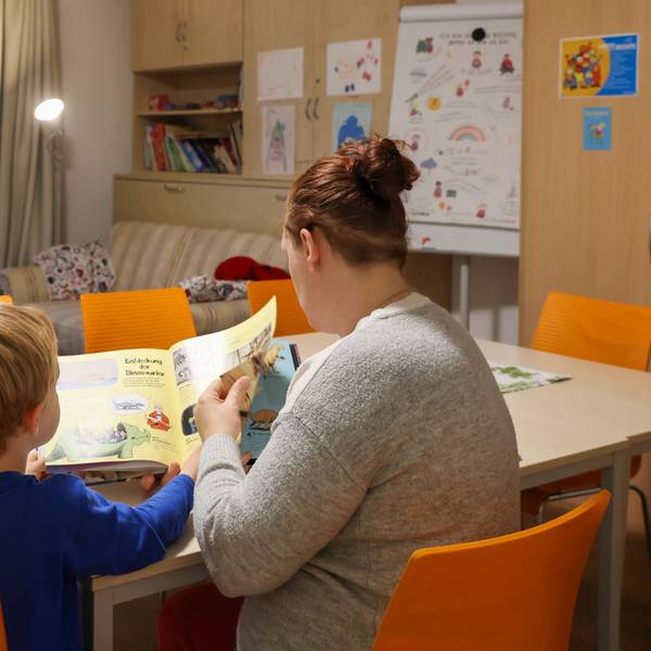 Ein Kind und eine Frau lesen in einem Buch.