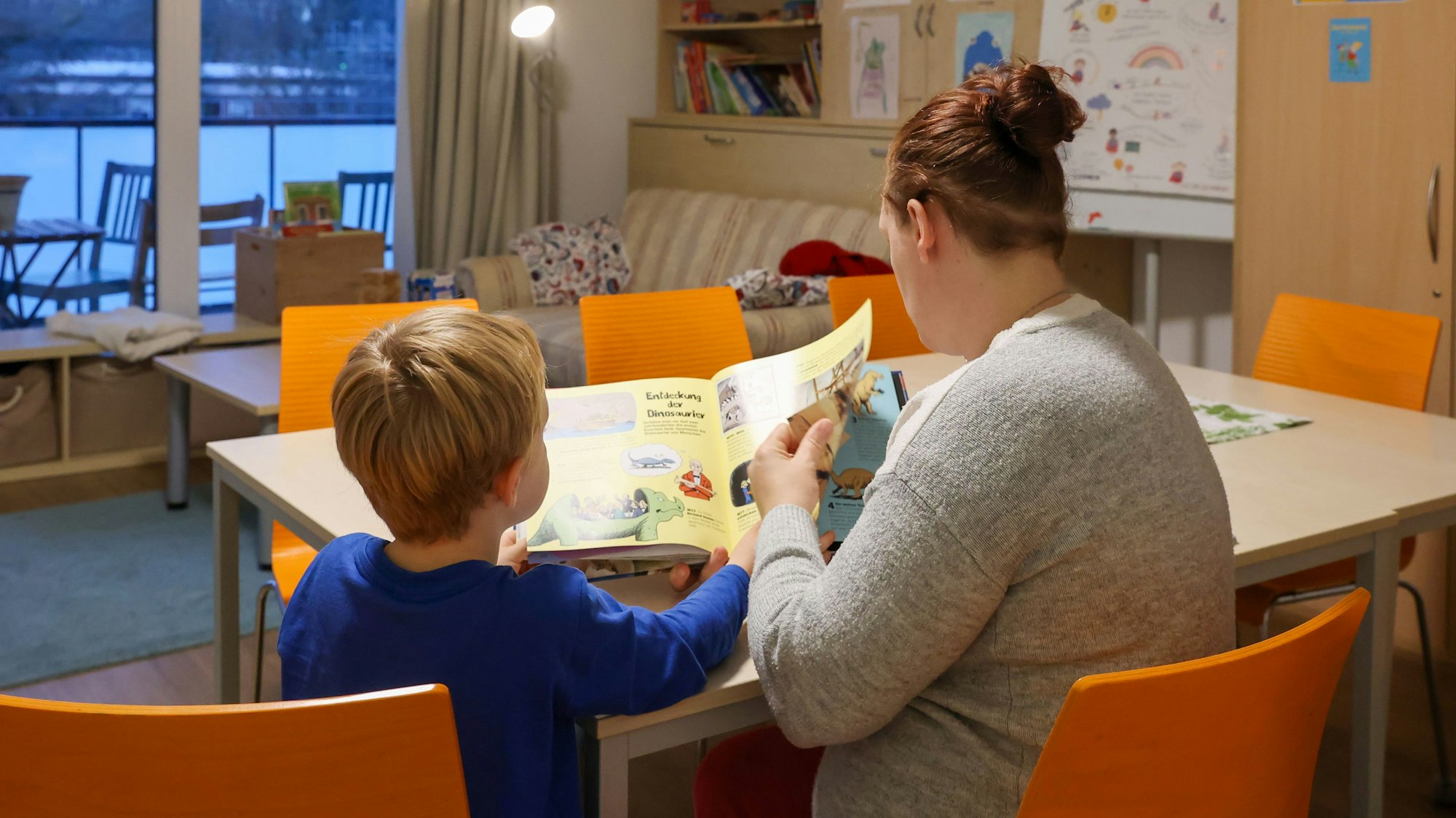 Ein Kind und eine Frau lesen in einem Buch.