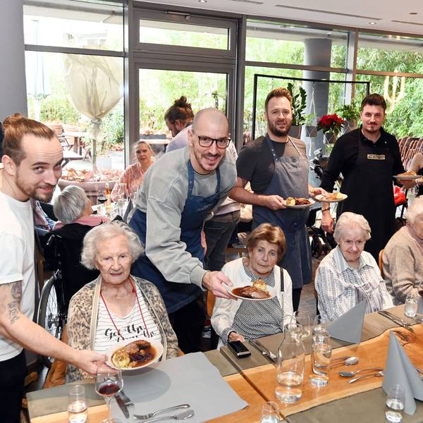 12.08.2025 Köln. Die gute Tat: Benefizaktion Gänseessen für Senioren der Diakonie Michaelshoven im Neobiota. Erik Scheffler (weißes T-Shirt) und Freunde servieren den Senieren das Essen. Foto: Alexander Schwaiger