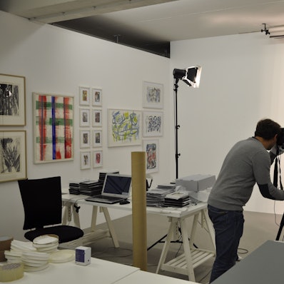 Ein Mann fotografiert ein Kunstwerk, es hängt an einer Wand.