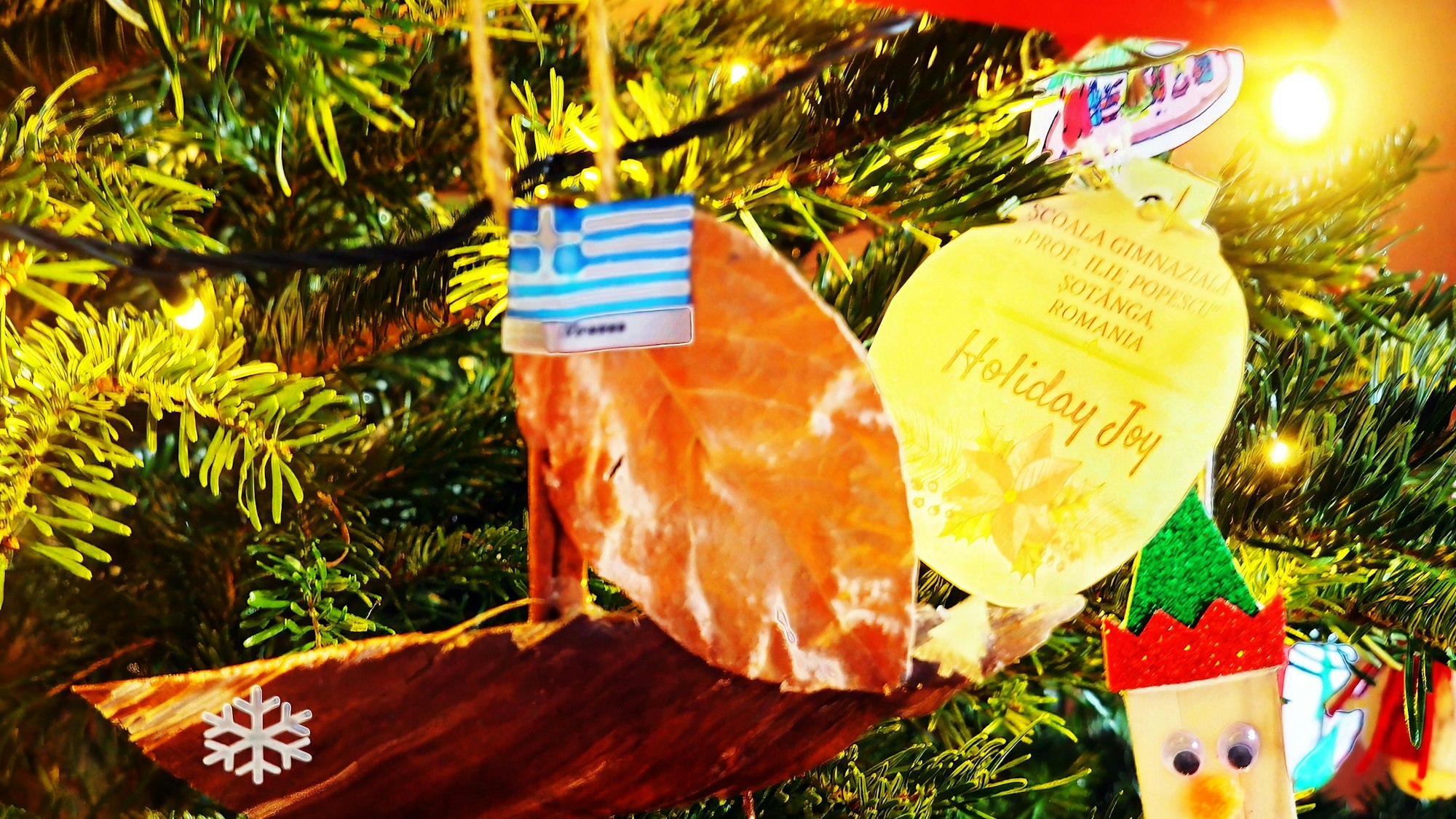 Ein Holzschiffchen mit griechischer Flagge hängt am Weihnachtsbaum.