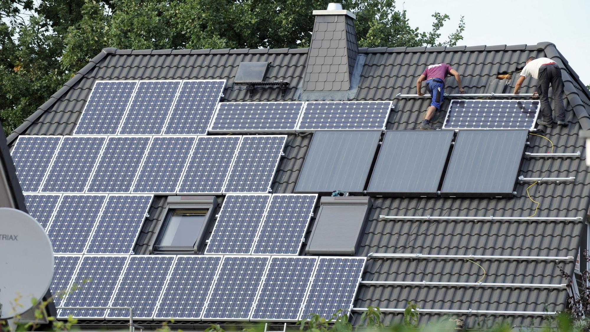Zwei Arbeiter auf einem Dachen, die Solaranlagen anbringen.