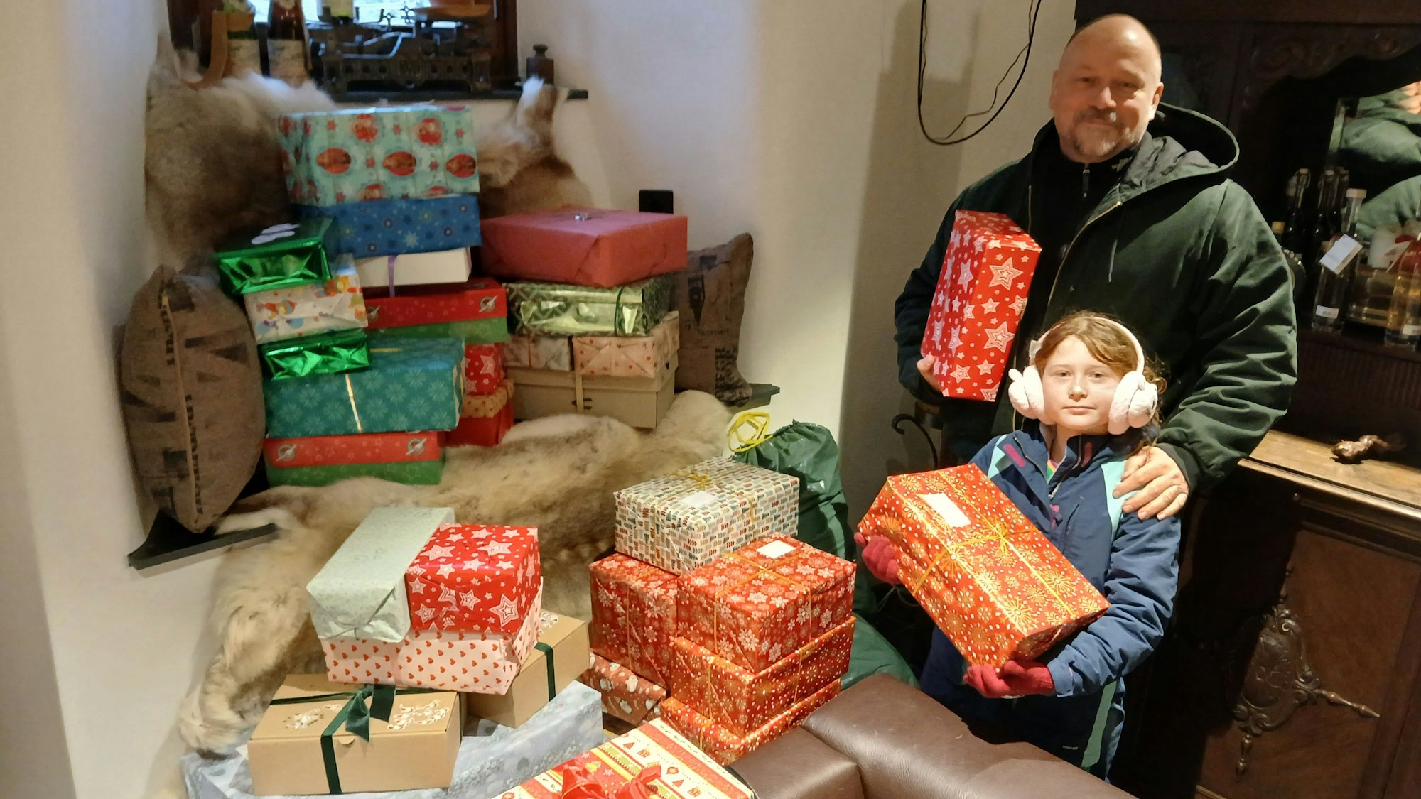 Ralf Oetinger steht mit seiner Tochter Emilia vor einem Berg von Weihnachtspäckchen.