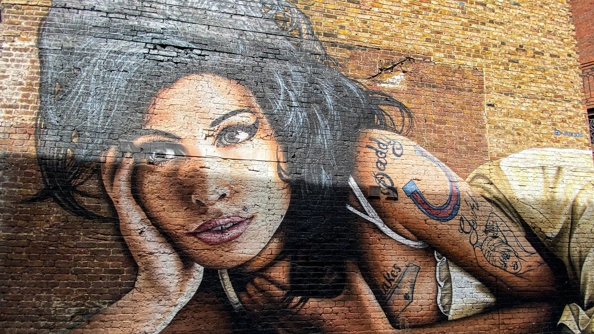 Wandgemälde von Amy Winehouse auf einer Ziegelwand.