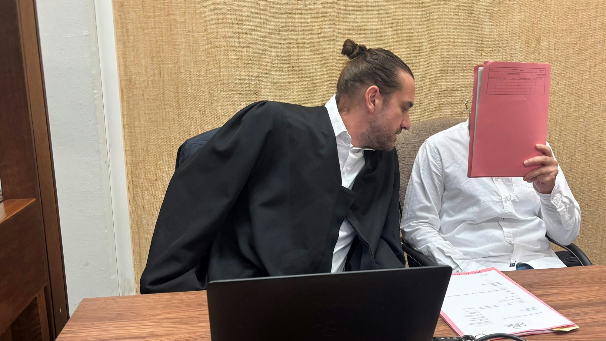 Das Bild zeigt einen Verteidiger und einen Angeklagten im Gericht.