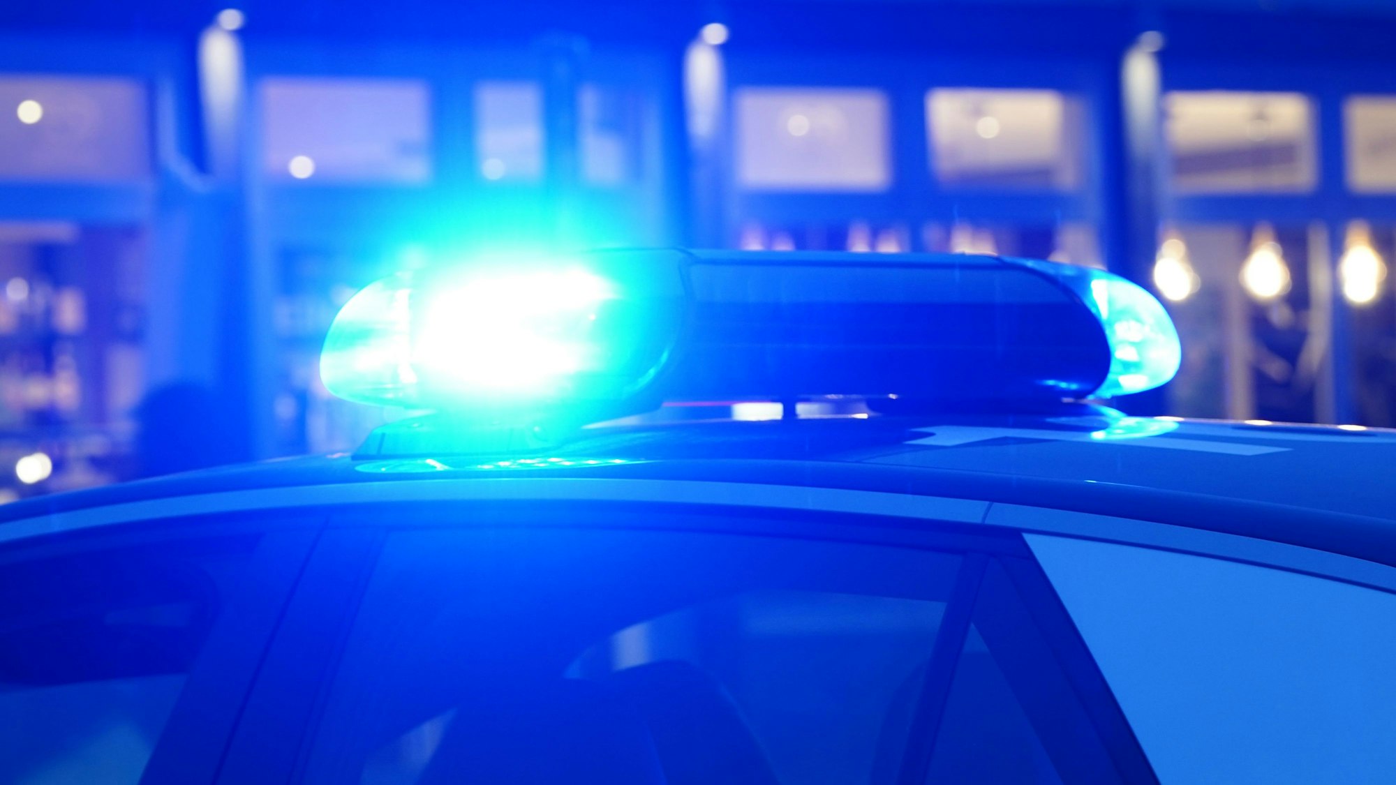 Ein Streifenwagen der Polizei steht mit eingeschaltetem Blaulicht an einem Einsatzort