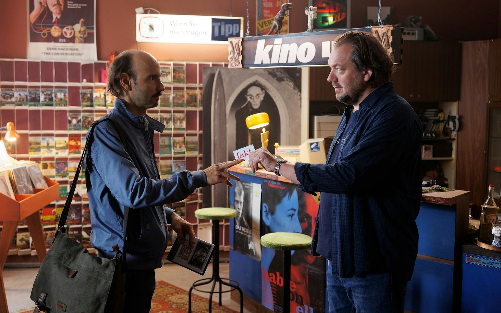 Michael (Charly Hübner, rechts) trifft in seiner Videothek auf einen Journalisten (Leon Ullrich), der ihn im Zentrum einer großen Heldengeschichte sieht. (Bild: X Verleih AG/Frédéric Batier)