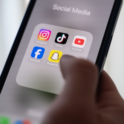 Das Bild zeigt eine Frau, die ein Smartphone hält, auf dessen Display verschiedene Social Media Apps angezeigt werden.
Foto: Alicia Windzio/dpa