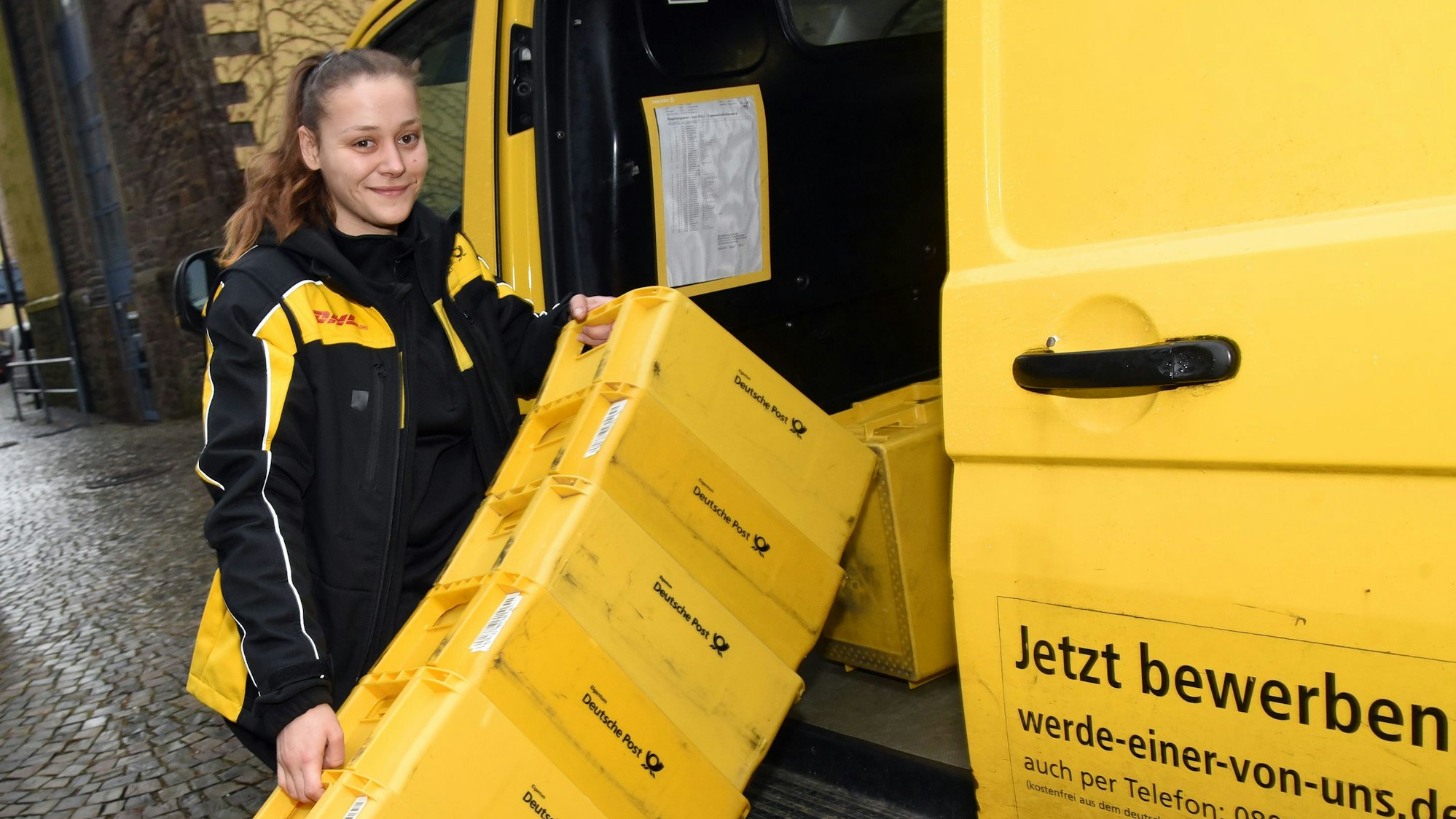 Anna Maria Schött lädt Postkisten in ein Postauto.
