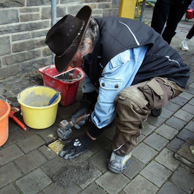 Das Foto zeigt den Künstler Gunter Demnig bei der Verlegung eines Stolpersteins