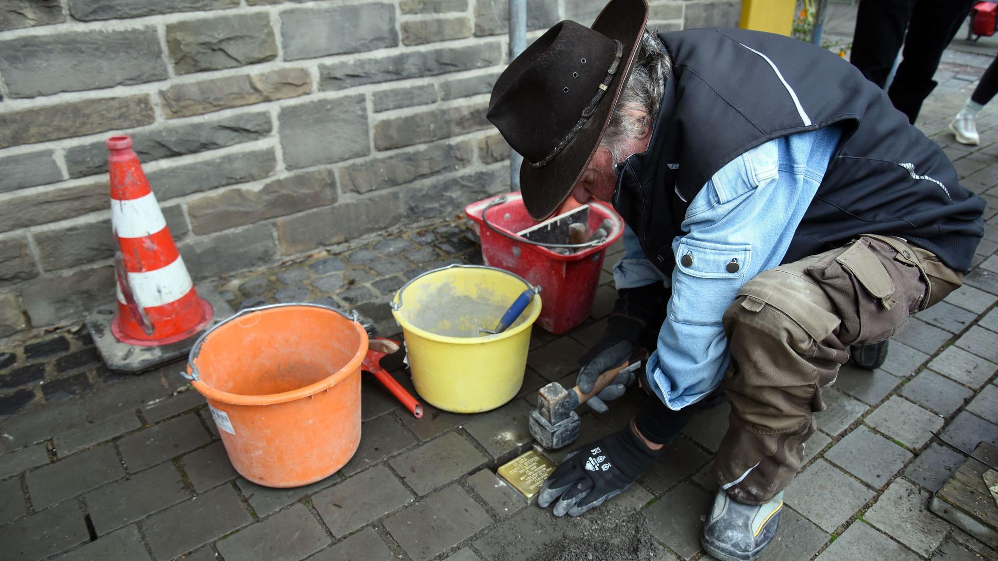 Das Foto zeigt den Künstler Gunter Demnig bei der Verlegung eines Stolpersteins