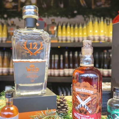 Das Bild zeigt eine Flasche des Brandes „Blutorangengeist“; im Hintergrund befinden sich Liköre.