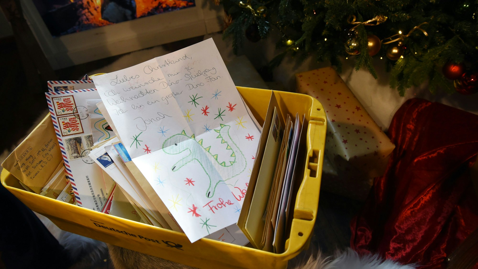 Wunschzettel stapeln sich in einer gelben Postbox.