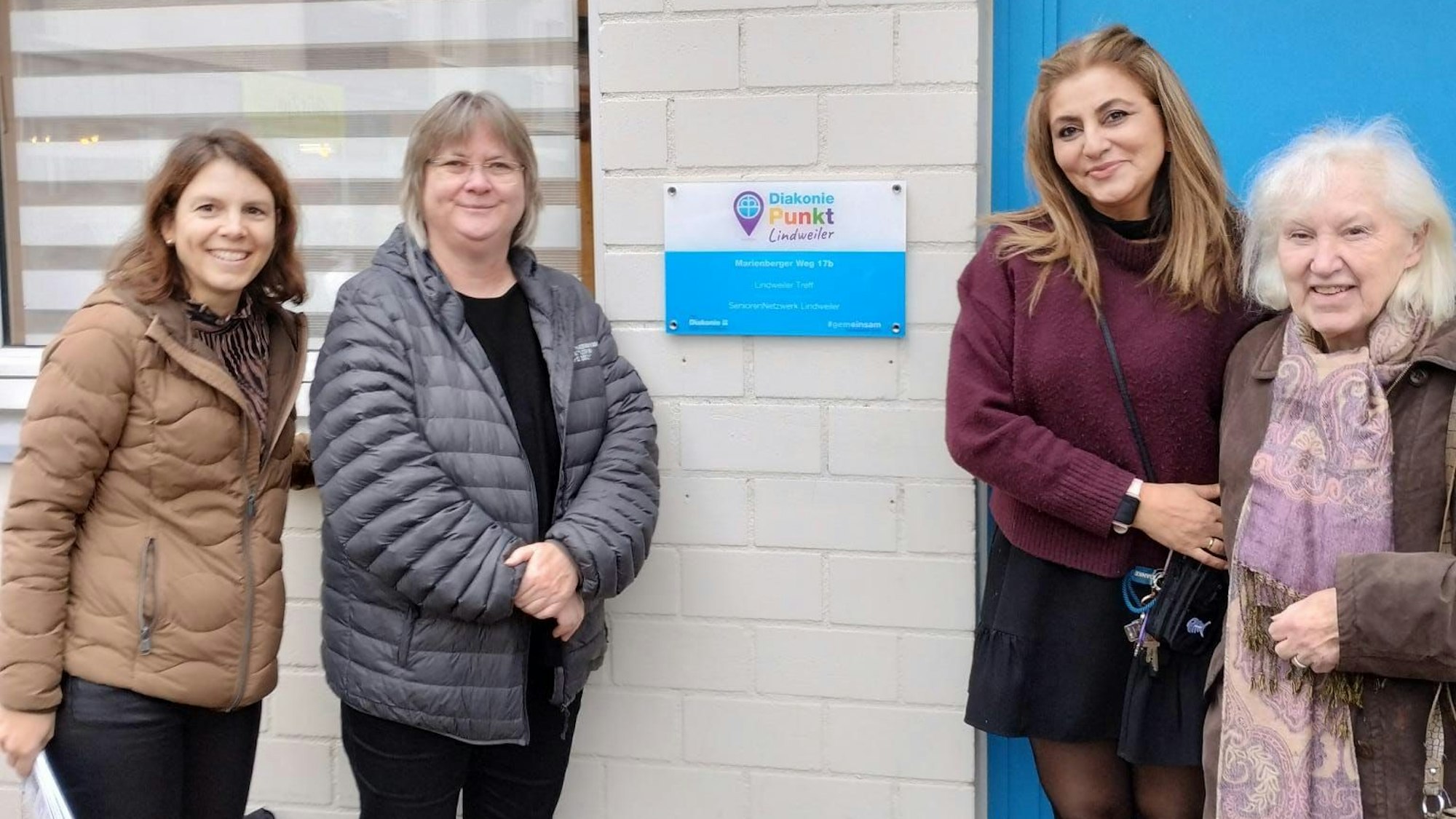 von links nach rechts: Diakonie-Vertreterin Marina von Ameln, Gemeindepfarrerin Sylvia Wacker, Treff-Leiterin Melek Henze und Wilfriede Kremp vom Seniorennetzwerk Lindweiler bei der Einweihung der Plakette, die den Lindweiler Treff als Diakoniepunkt ausweist.