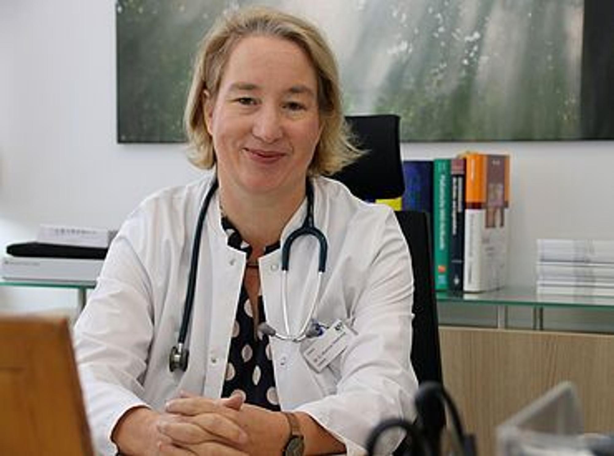 Dr. Cordula Koerner-Rettberg in ihrer Praxis am Schreibtisch mit Stetoskop um den Hals.