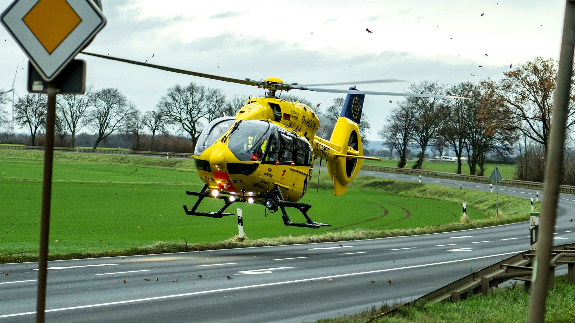 Das Bild zeigt einen Rettungshubschrauber, der auf einer gesperrten Straße landet.