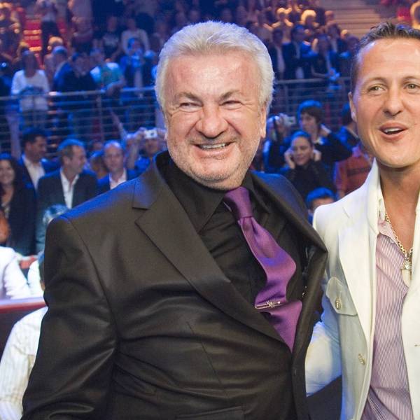 Willi Weber und Michael Schumacher stehen nebeneinander und lachen.