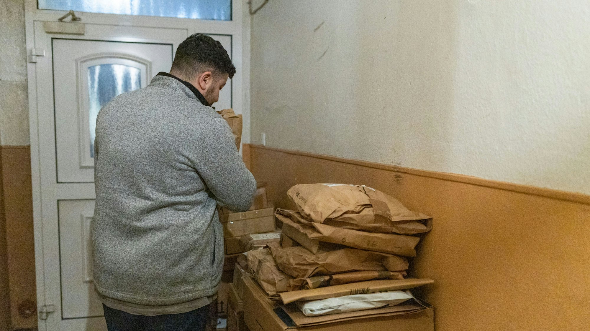 Ein Mann sortiert Pakete im Hausflur.