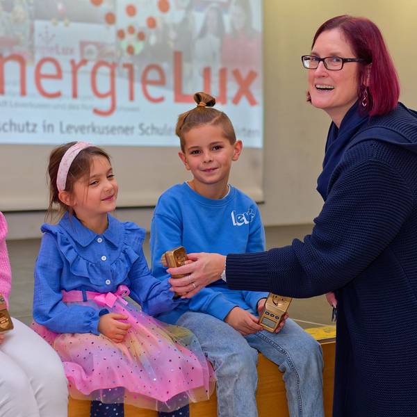 Alina von der Realschule am Stadtpark, Sophie von der Kita Heinrich-Lübke-Straße und Louis von der Hans-Christian -Andersen Schule erhalten das „goldene Energiesparmessgerät“ von Bezirksbürgermeisterin Michaela Di Padova.