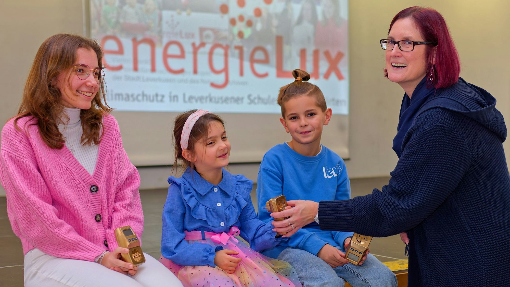 Alina von der Realschule am Stadtpark, Sophie von der Kita Heinrich-Lübke-Straße und Louis von der Hans-Christian -Andersen Schule erhalten das „goldene Energiesparmessgerät“ von Bezirksbürgermeisterin Michaela Di Padova.