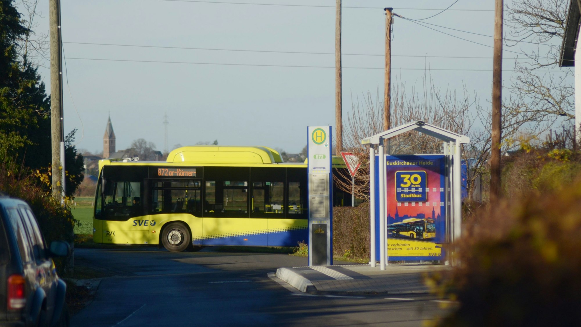 Im Vordergrund ist die Haltestelle zu sehen, dahinter der Bus.