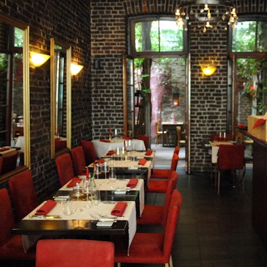 Das Restaurant Limbourg in der Limburger Straße im belgischen Viertel
von innen mit Theke, roten Stühlen und gedeckten Tischen.