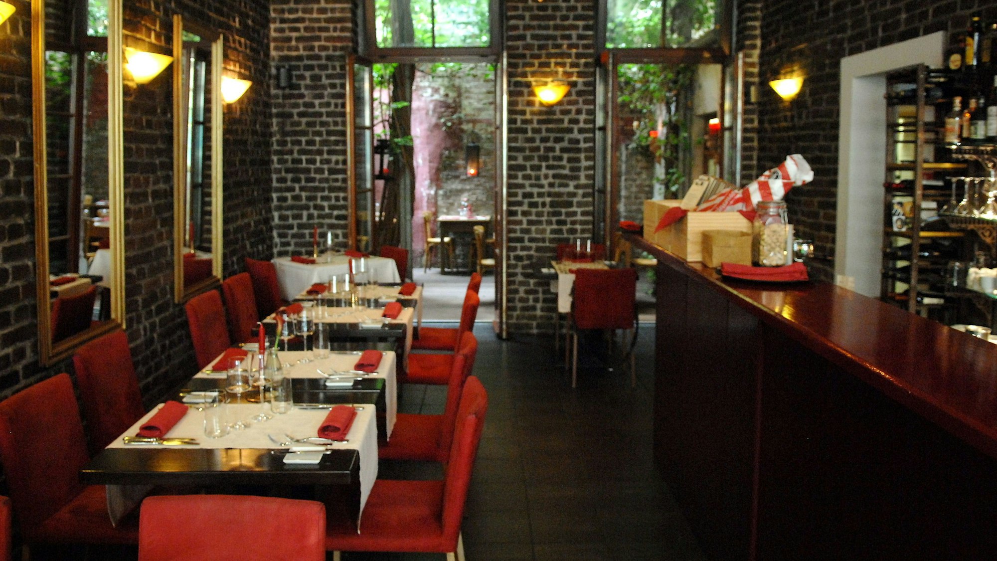 Das Restaurant Limbourg in der Limburger Straße im belgischen Viertel
von innen mit Theke, roten Stühlen und gedeckten Tischen.