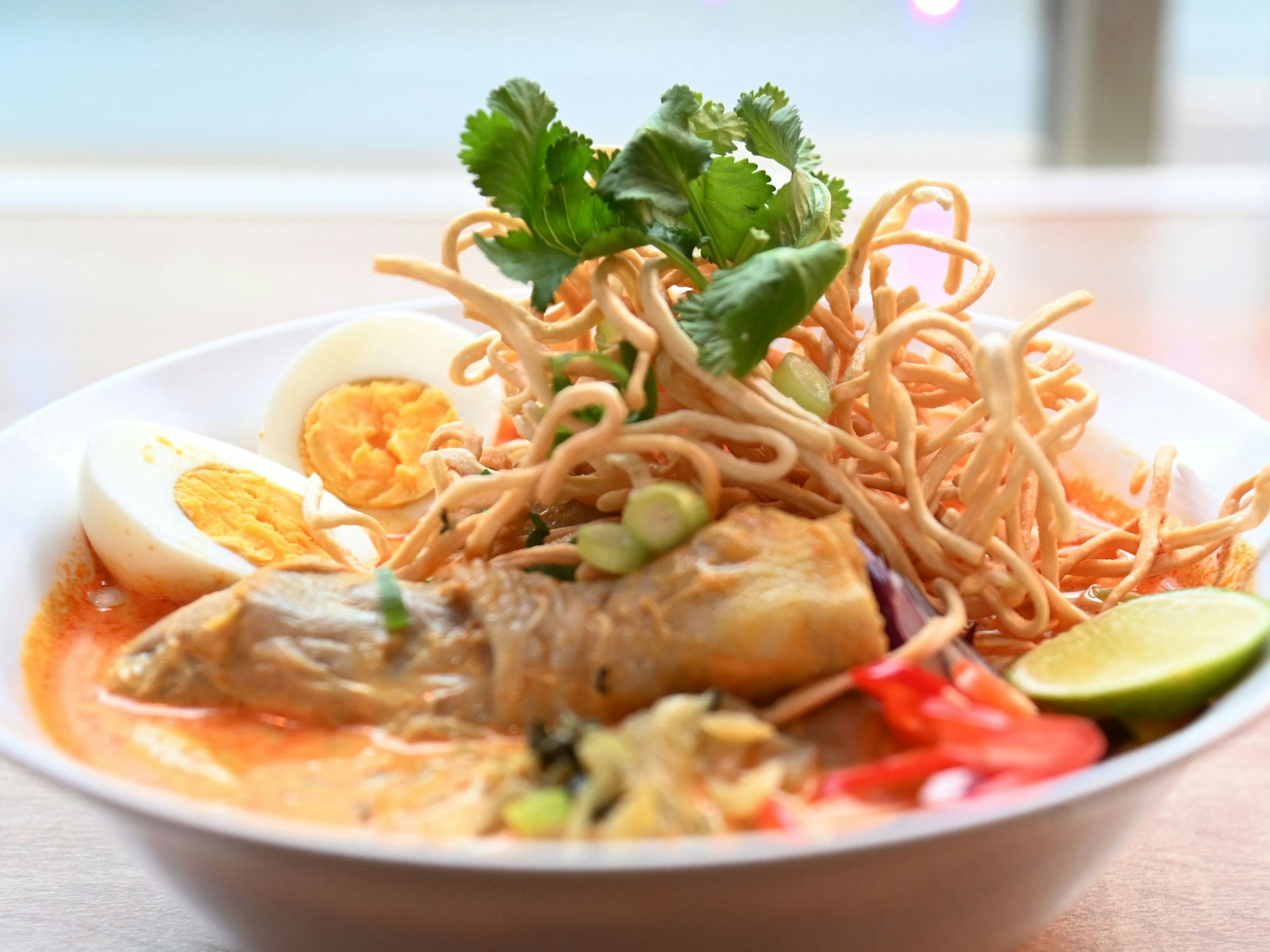 Eine Schale Suppe mit hartgekochtem Ei, Nudeln und Koriander dekoriert