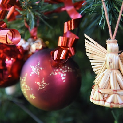 Ein Engel und zwei Weihnachtskugeln hängen in einem Baum.