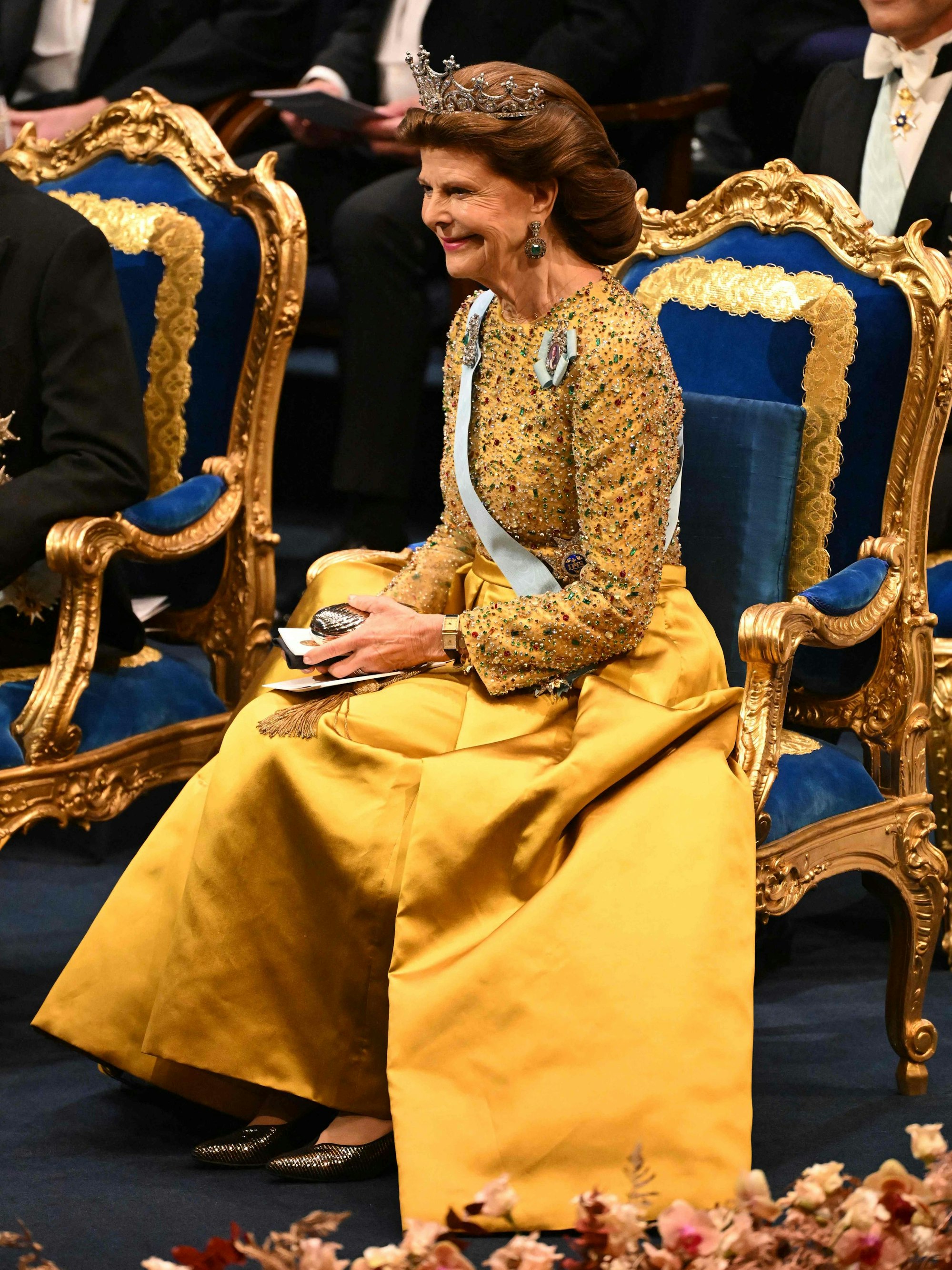Königin Silvia sitzt auf einem Stuhl.