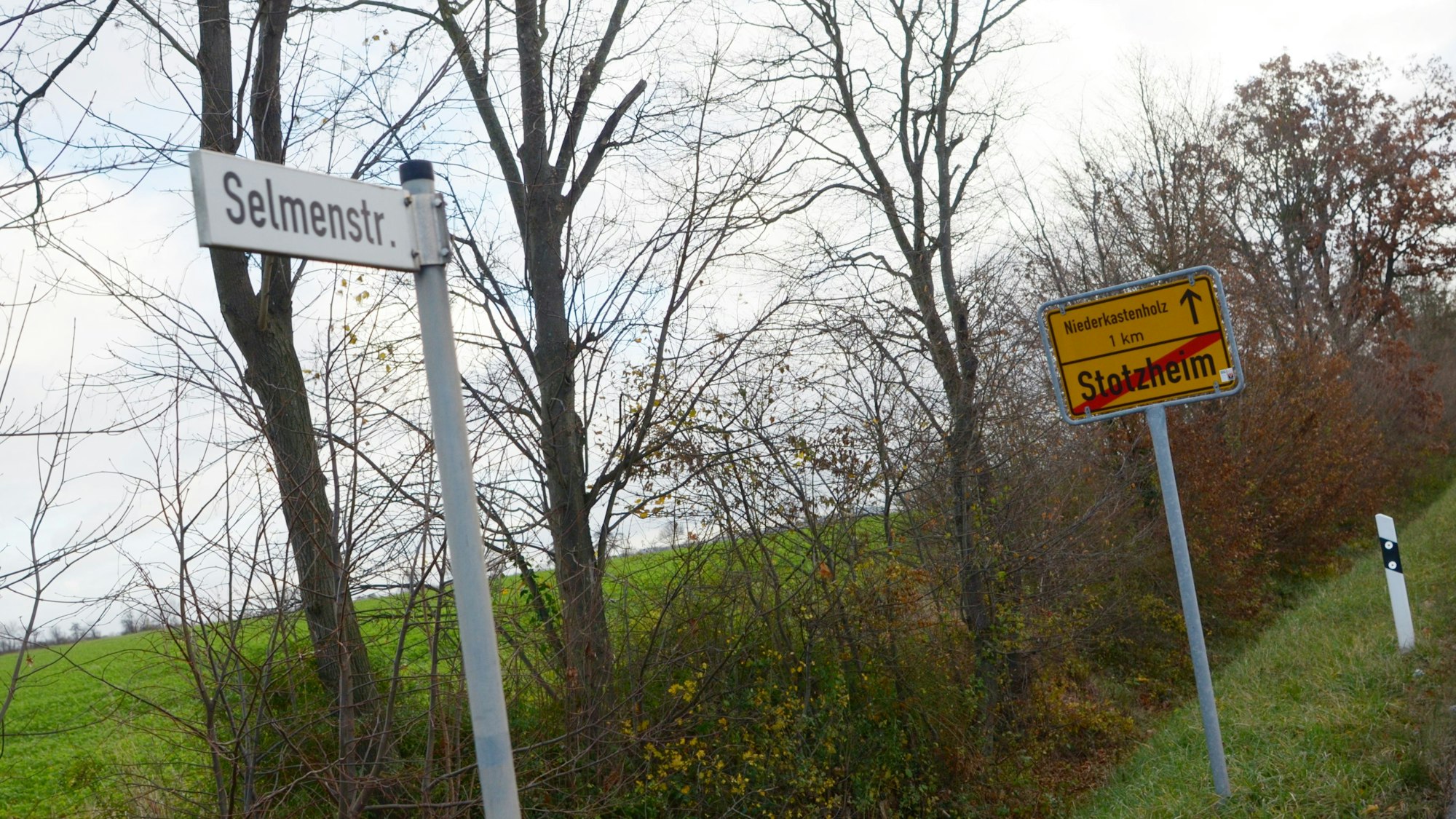 Auf dem Foto sieht man das Schild mit dem Namen Selmenstraße, im Hintergrund steht das Ortsausgangsschild von Stotzheim.