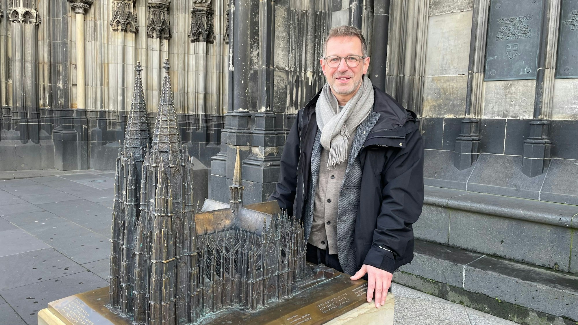 Ein Mann steht auf dem Vierungsturm des Kölner Doms, hinter ihm ragen die beiden Domtürme in den Himmel.