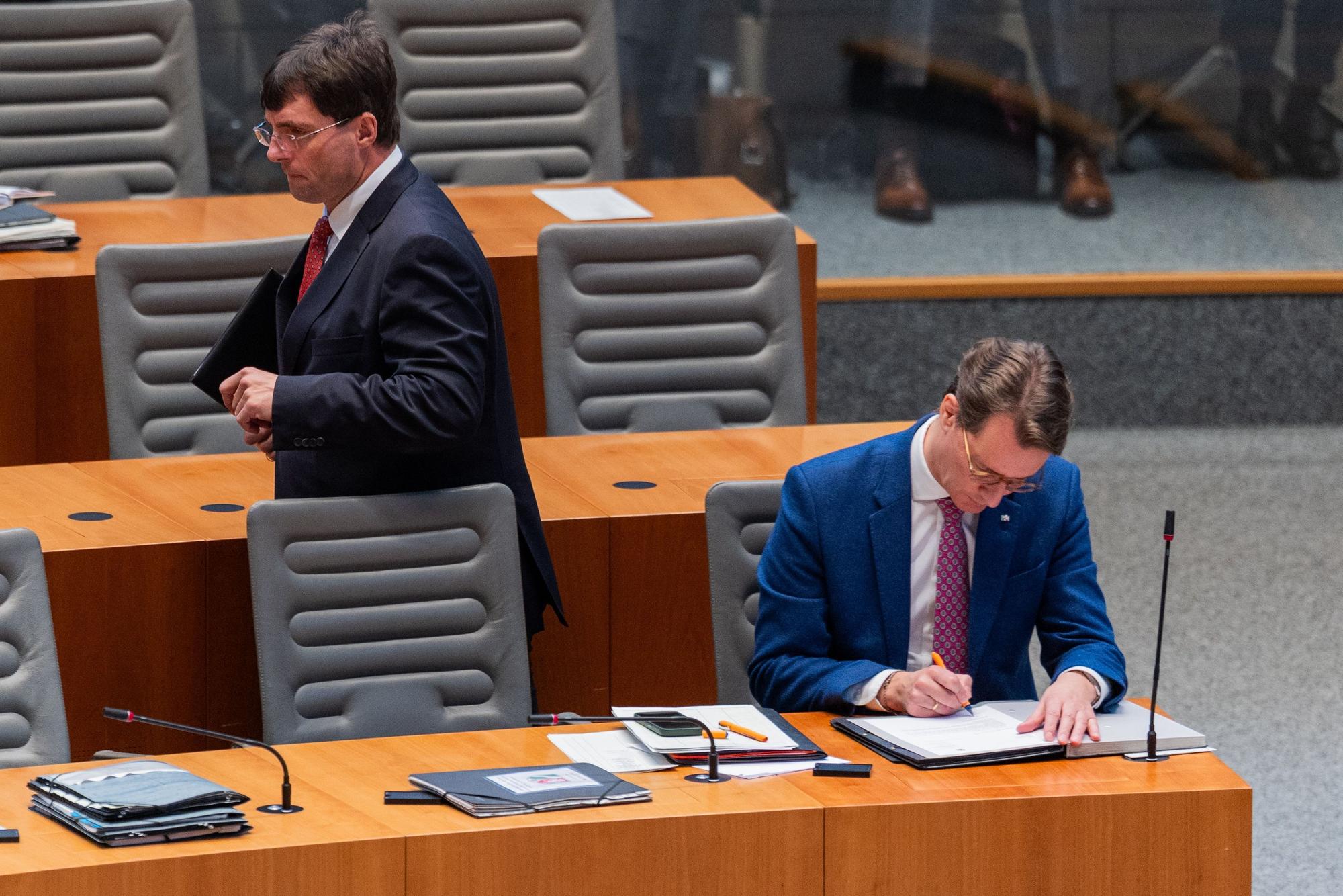 Marcus Optendrenk (l, CDU), Finanzminister von Nordrhein-Westfalen, geht an Hendrik Wüst (CDU), Ministerpräsident von Nordrhein-Westfalen, im Plenum des Landtags vorbei.
