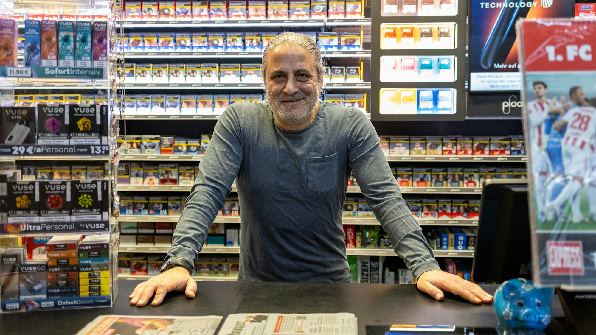 Ein Mann steht in einem Kiosk und schaut in die Kamera.