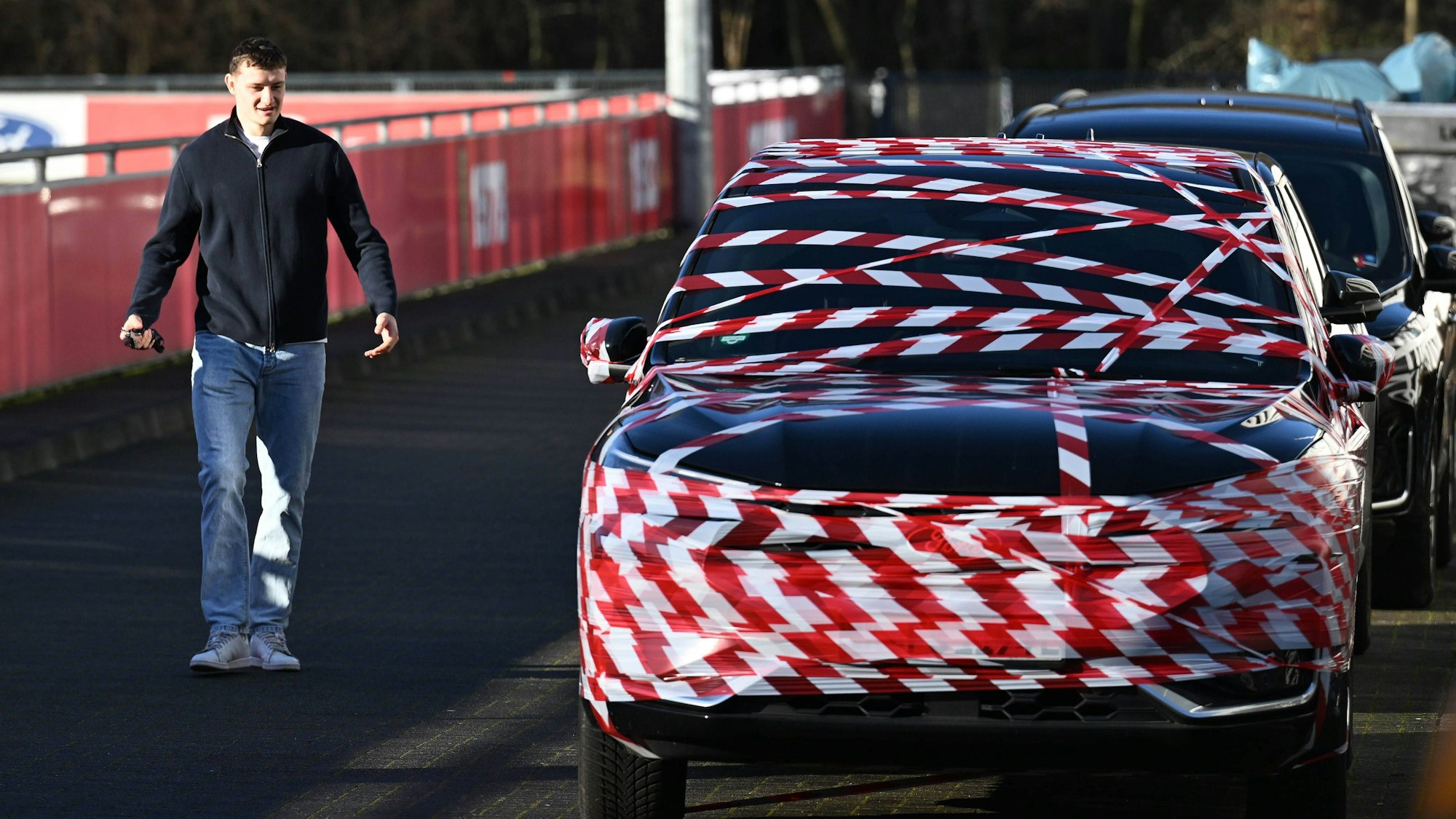 Eric Martel kommt zu seinem Auto, das mit rot-weißem Flatterband umhüllt ist.