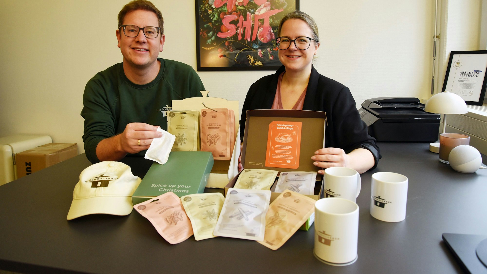 Die zwei Firmengründer sitzen mit Geschmack-Sack-Produkten vor sich an einem Tisch.