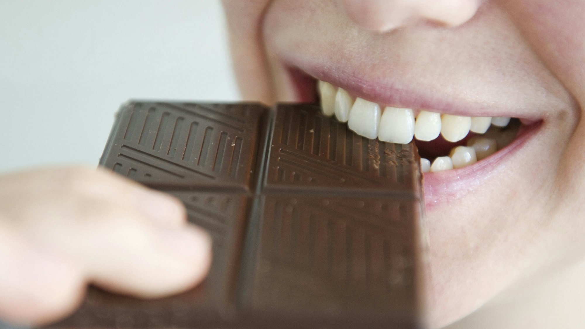 Frau beißt in Schokolade.