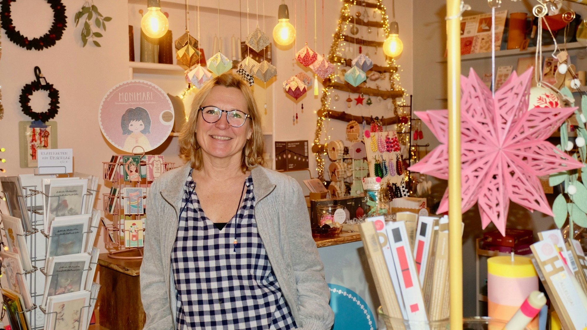 Eine Frau mit blondem Haar steht in einem Laden voller Dekorartikel.